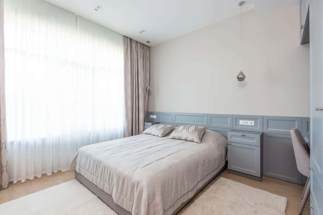 Bright, calm guest bedroom with a made bed and sheer curtains - guest suite builders, Ontario, Canada