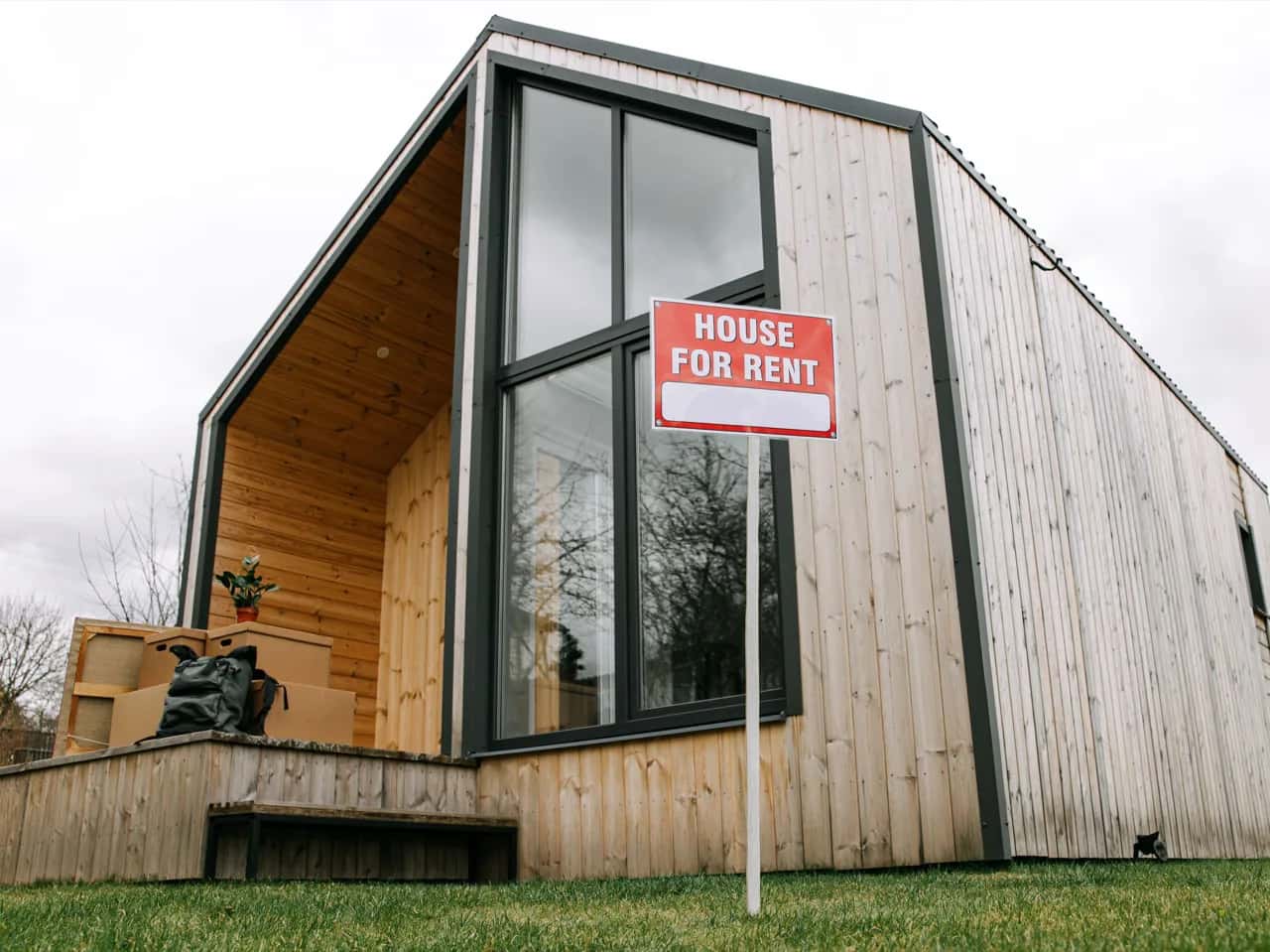 Modern timber-clad backyard dwelling with a for-rent sign on the lawn - investment property ADU builders, Ontario, Canada
