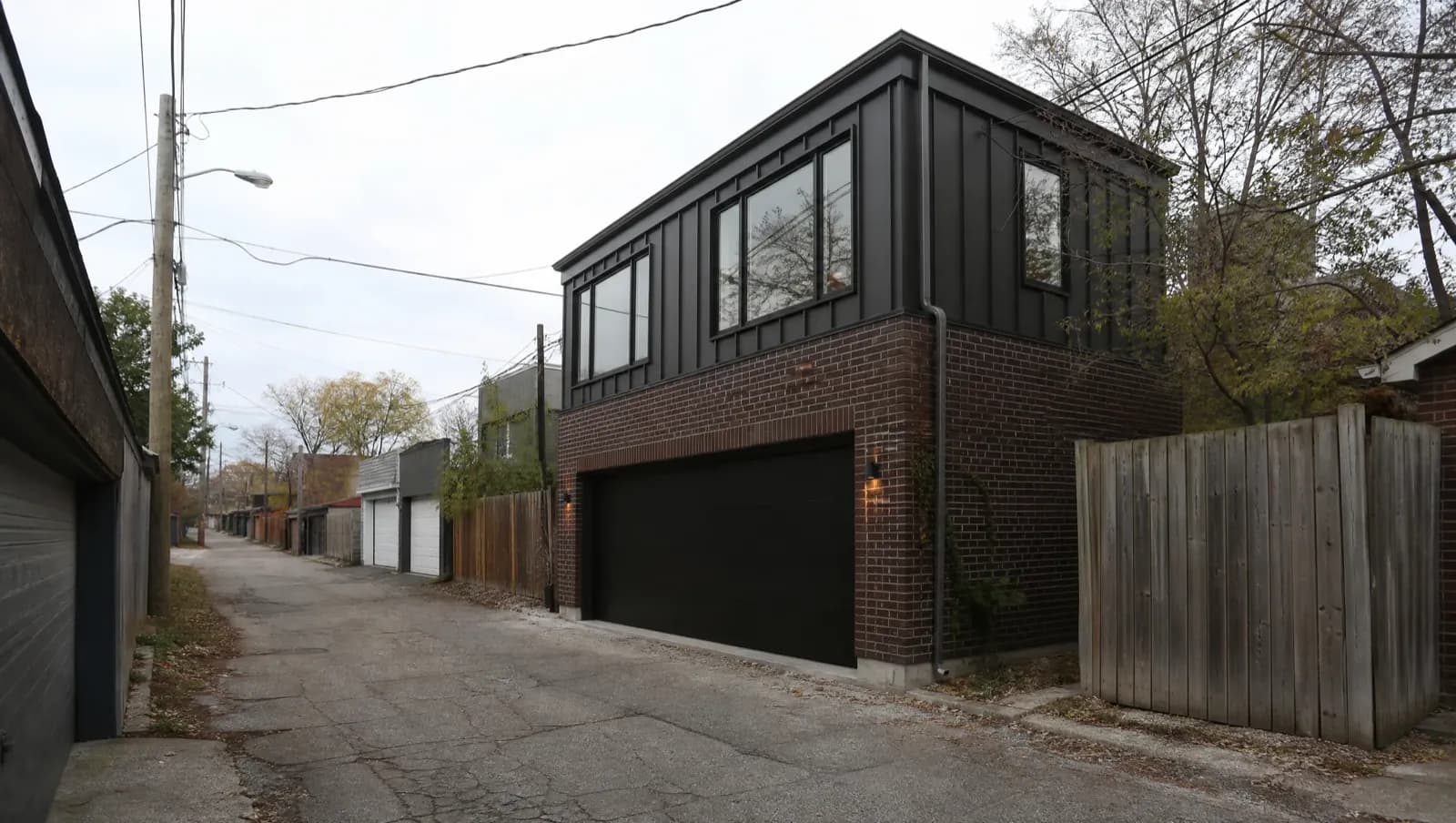 Black-and-brick two-storey laneway home with a garage door, seen from a Toronto rear lane - laneway home versus garden suite, Ontario, Canada