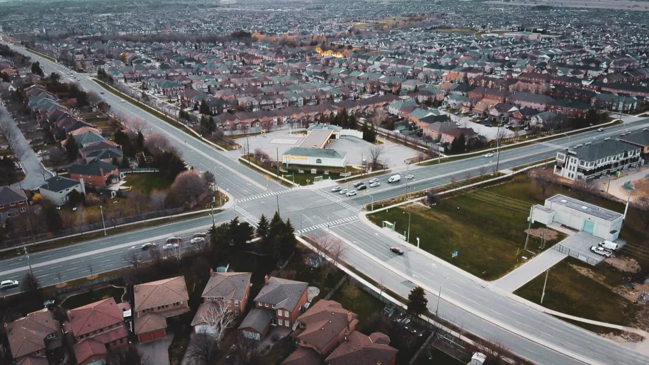 Aerial view of a suburban Ontario town - an arterial road, retail plazas and brick subdivisions - ADU builders serving Milton, Ontario, Canada