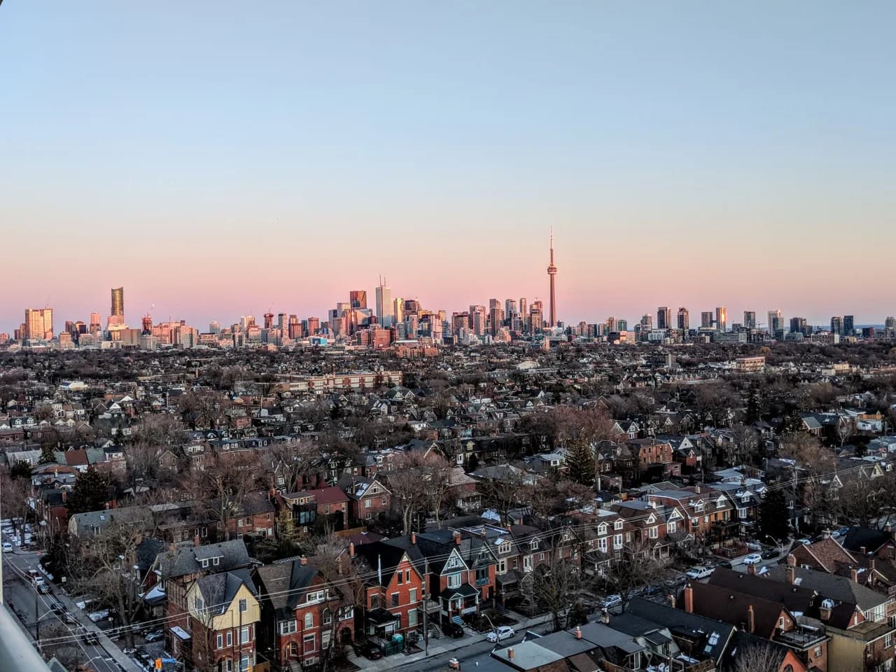 Low-rise residential York rooftops at dusk with the downtown Toronto skyline on the horizon - ADU builders serving York, Ontario, Canada