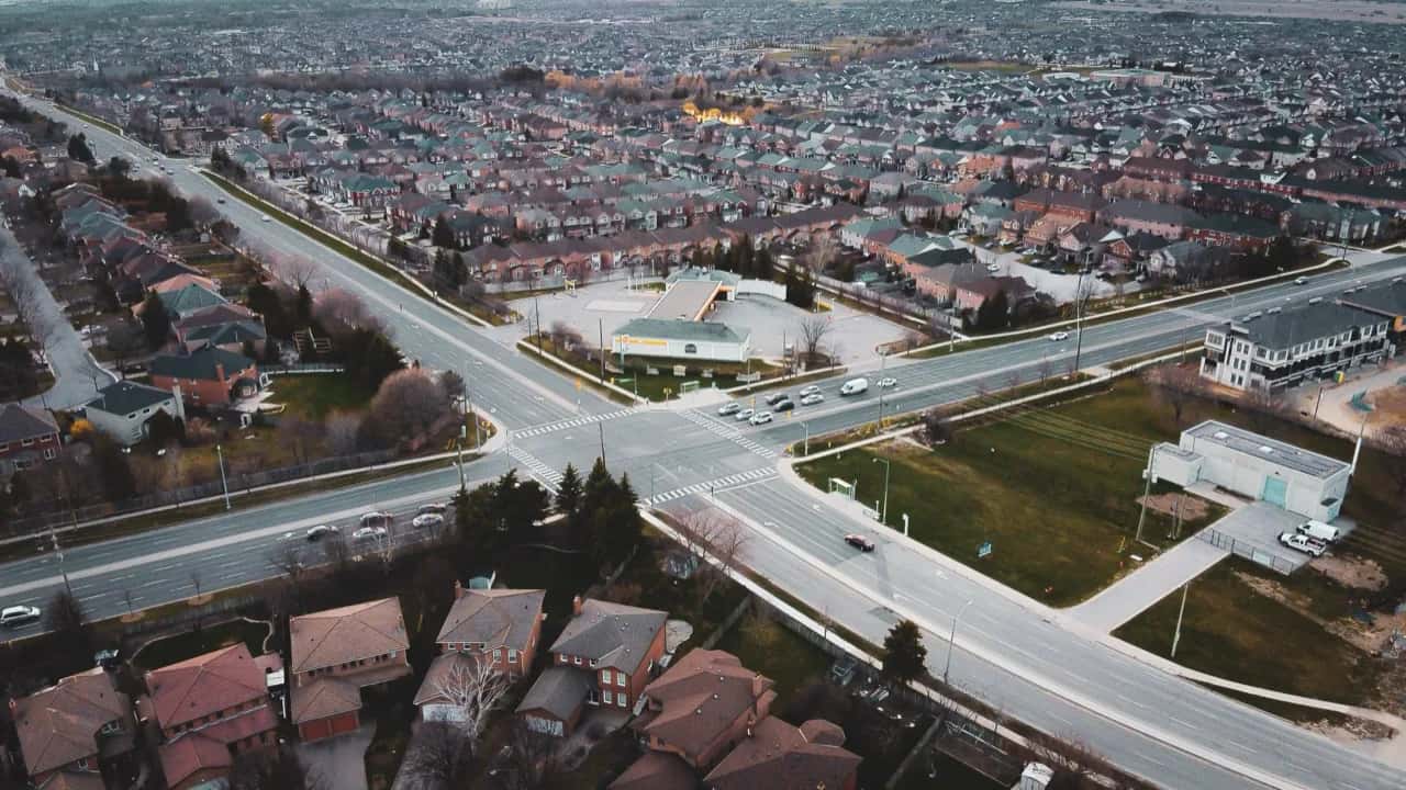 Aerial view of a suburban Ontario town - an arterial road, retail plazas and brick subdivisions - ADU builders serving Milton, Ontario, Canada