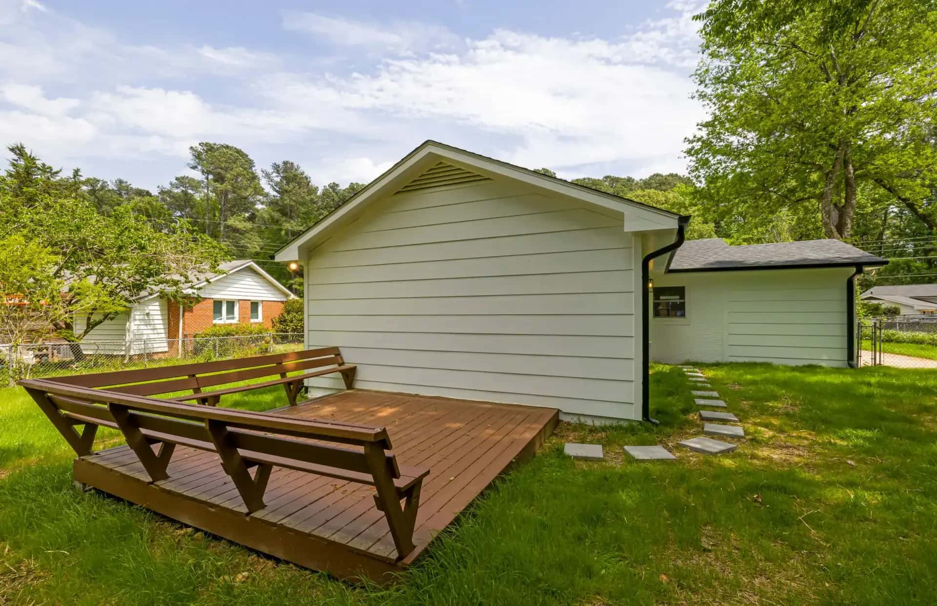 Detached backyard dwelling with pale siding and a wide wooden deck in a residential yard, Greater Toronto Area, Ontario, Canada