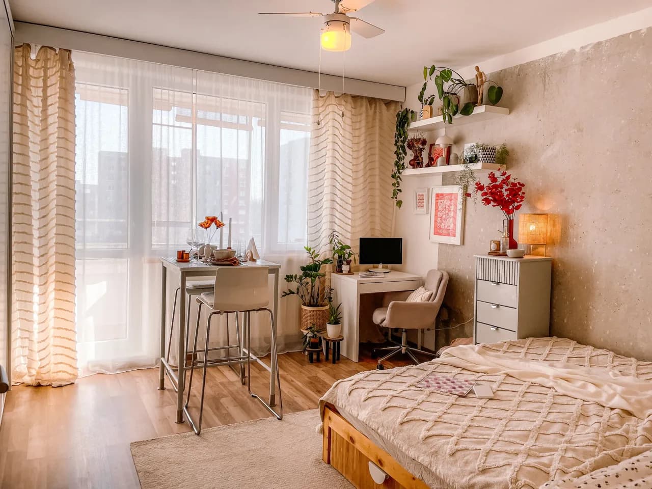 Compact studio suite with a bed, desk workstation and plants by a bright window - student rental suite builders, Ontario, Canada